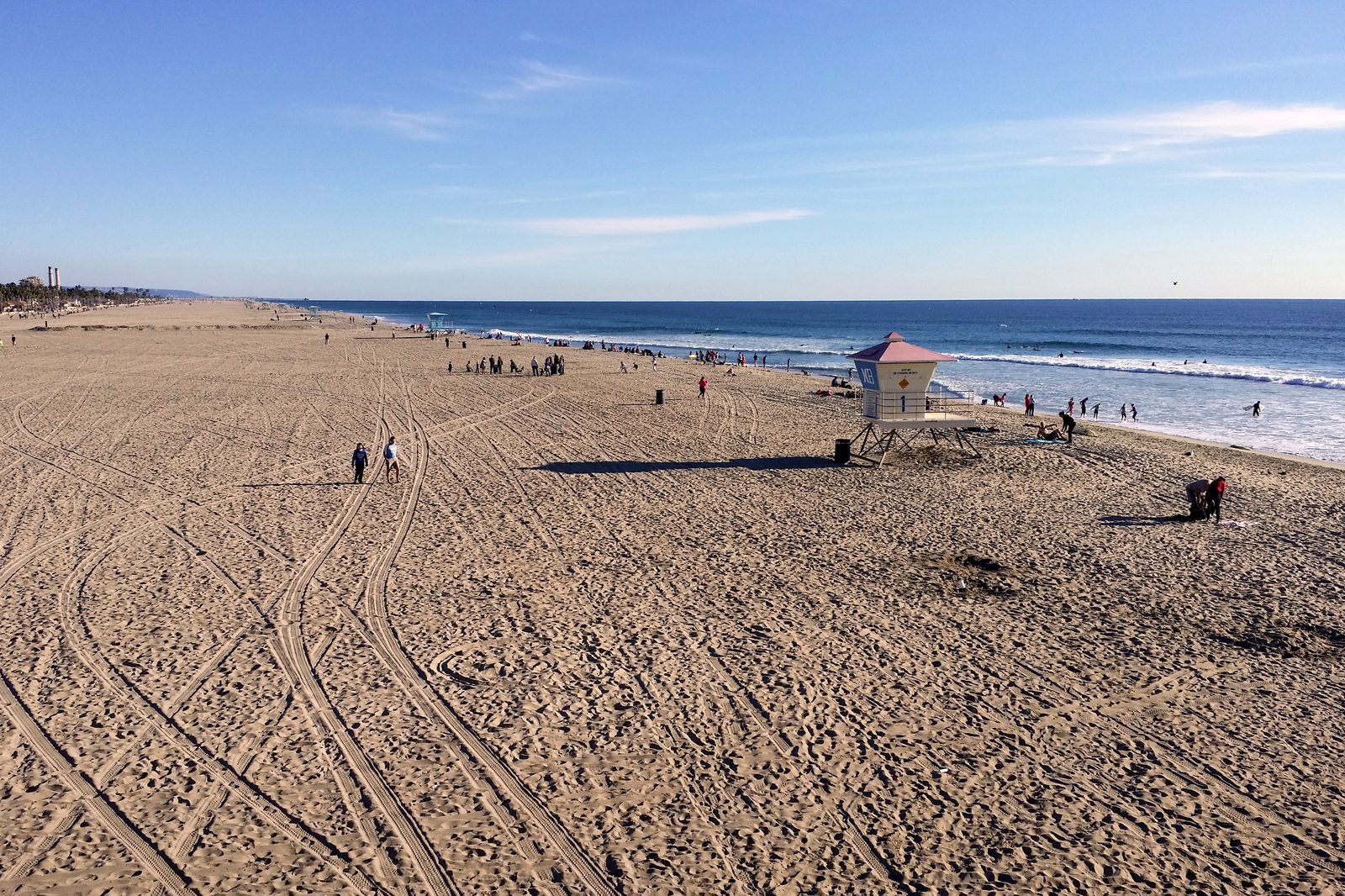 The Huntington Beach shoreline and a lifeguard tower. Officials searched by drone, jet ski and rescue boat but could not independently confirm the sighting, and planned added patrols before reopening.