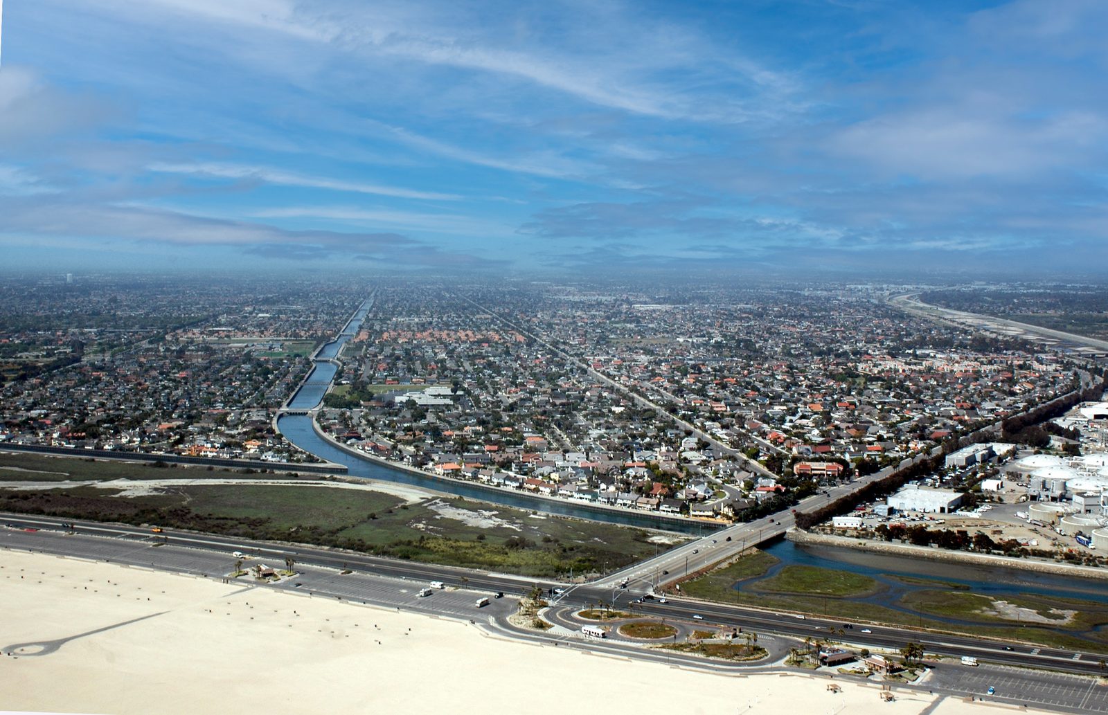 An aerial view of the Huntington Beach shoreline, Pacific Coast Highway and the neighborhoods behind the Santa Ana River mouth. The advisory covers the Orange County coastal areas, with overnight lows only in the high 60s to low 70s.