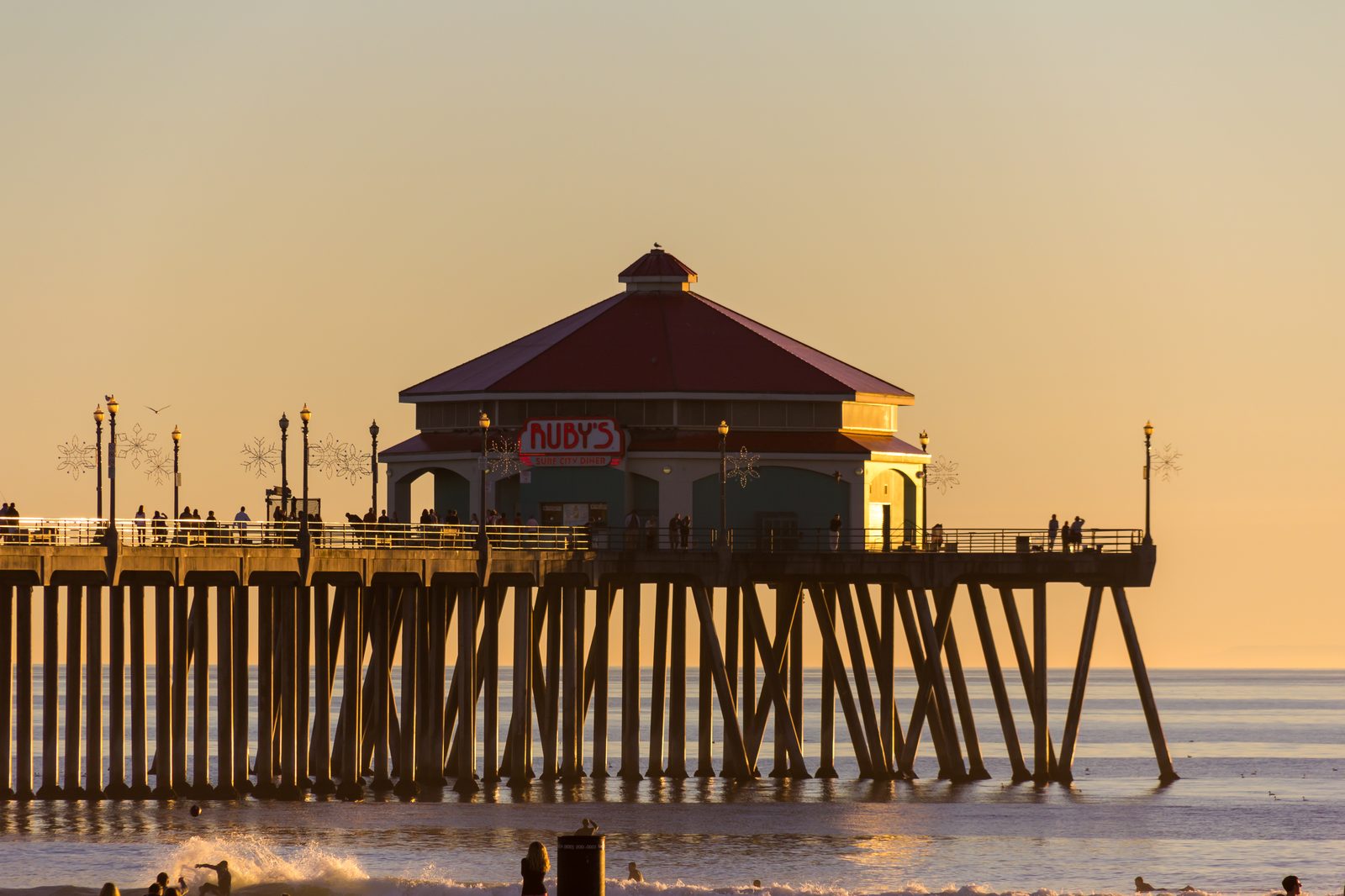 Waves break around the pilings of the Huntington Beach Pier, where Ruby's sits at the end. Forecasters warn Rachel's swells will keep building along the coast through the weekend.