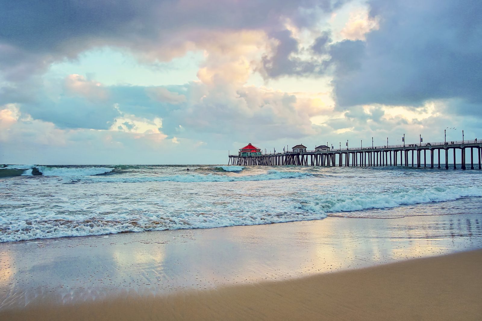 File photo: storm clouds gather over the Huntington Beach Pier as surf breaks on the sand. The beach hazards statement runs through 11 p.m. Tuesday, with surf of 3 to 5 feet and local sets to 6 feet.