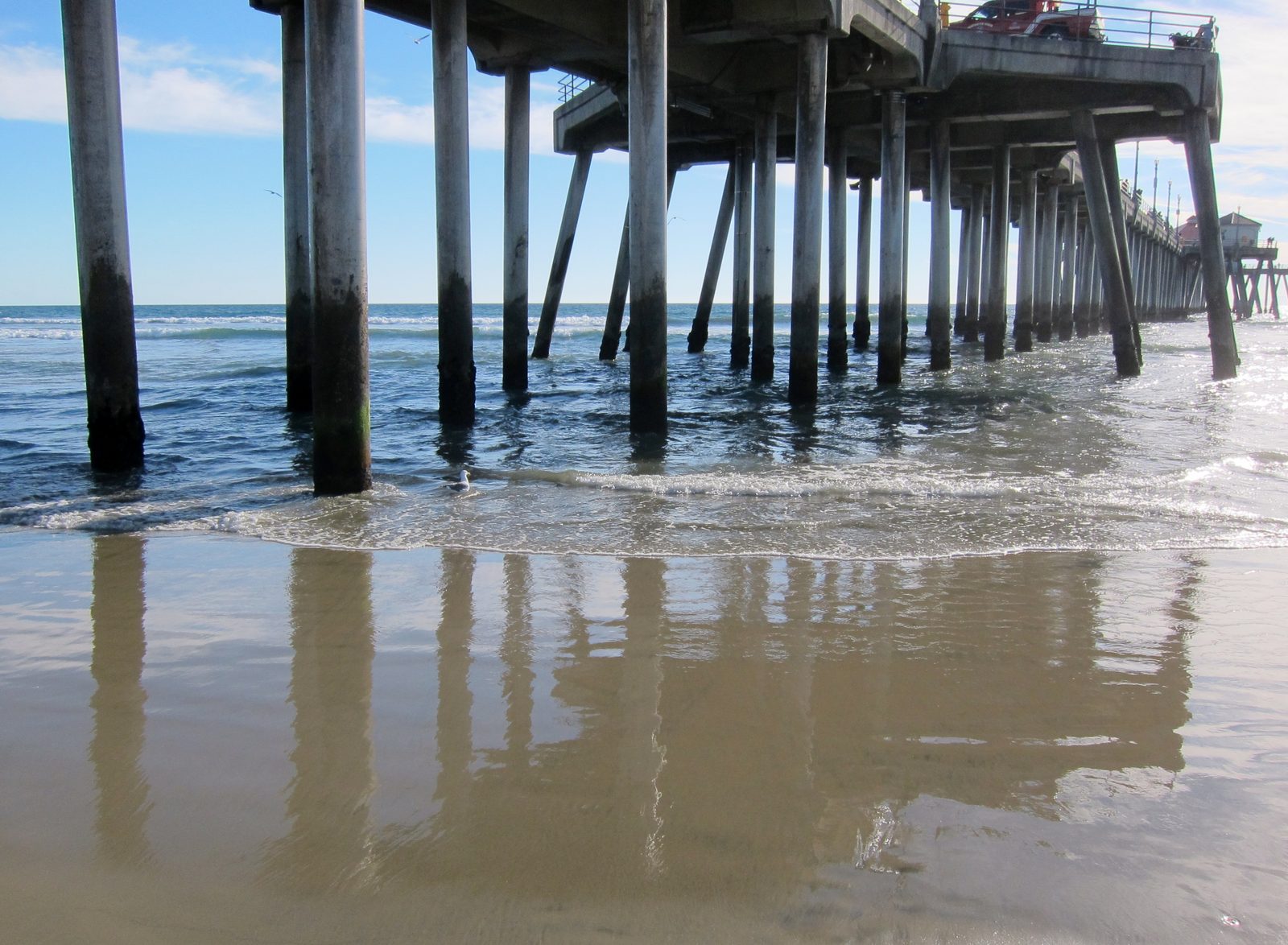 Waves roll beneath the pilings of the Huntington Beach Pier. A coastal flood warning covers Orange County coastal areas through 3 p.m. Sunday.