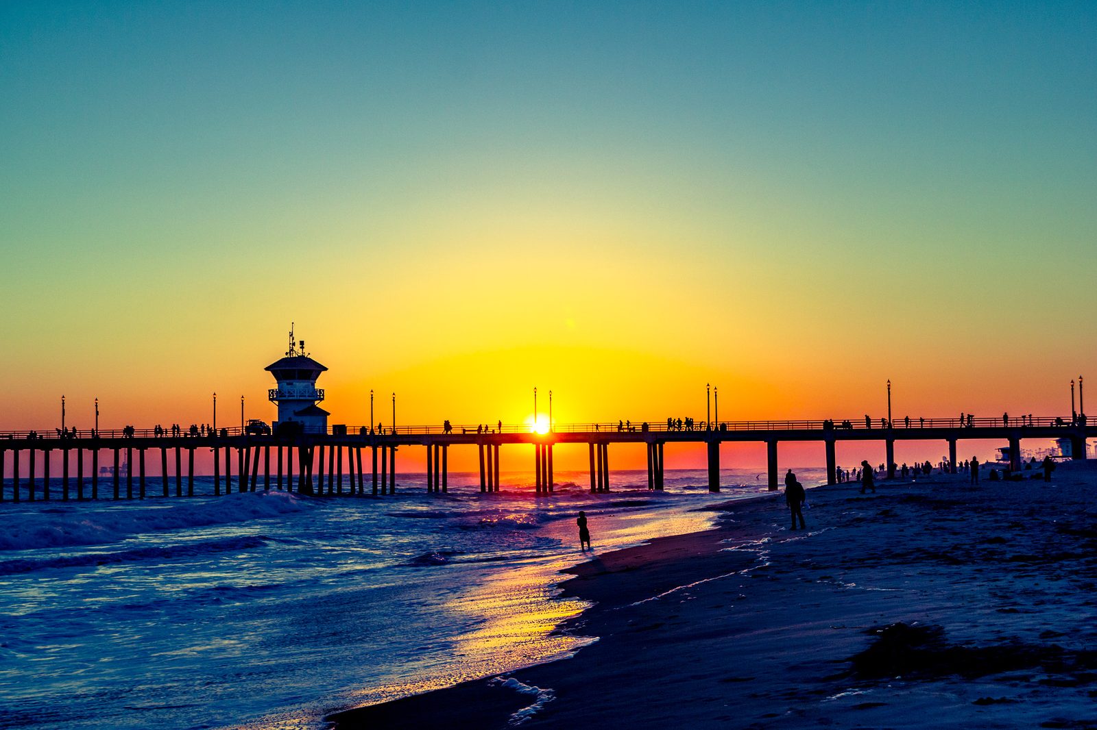 The sun sets behind the Huntington Beach Pier. Sunday's morning high tide brings the weekend's worst flooding risk as swells, onshore winds and high tides combine.