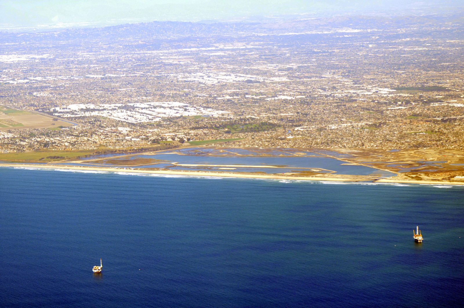 Bolsa Chica State Beach from above, with its shoreline fronting the ocean. A beach hazards statement runs from 6 a.m. to 10 p.m. Sunday, with surf of 5 to 7 feet and local sets up to 9 feet.