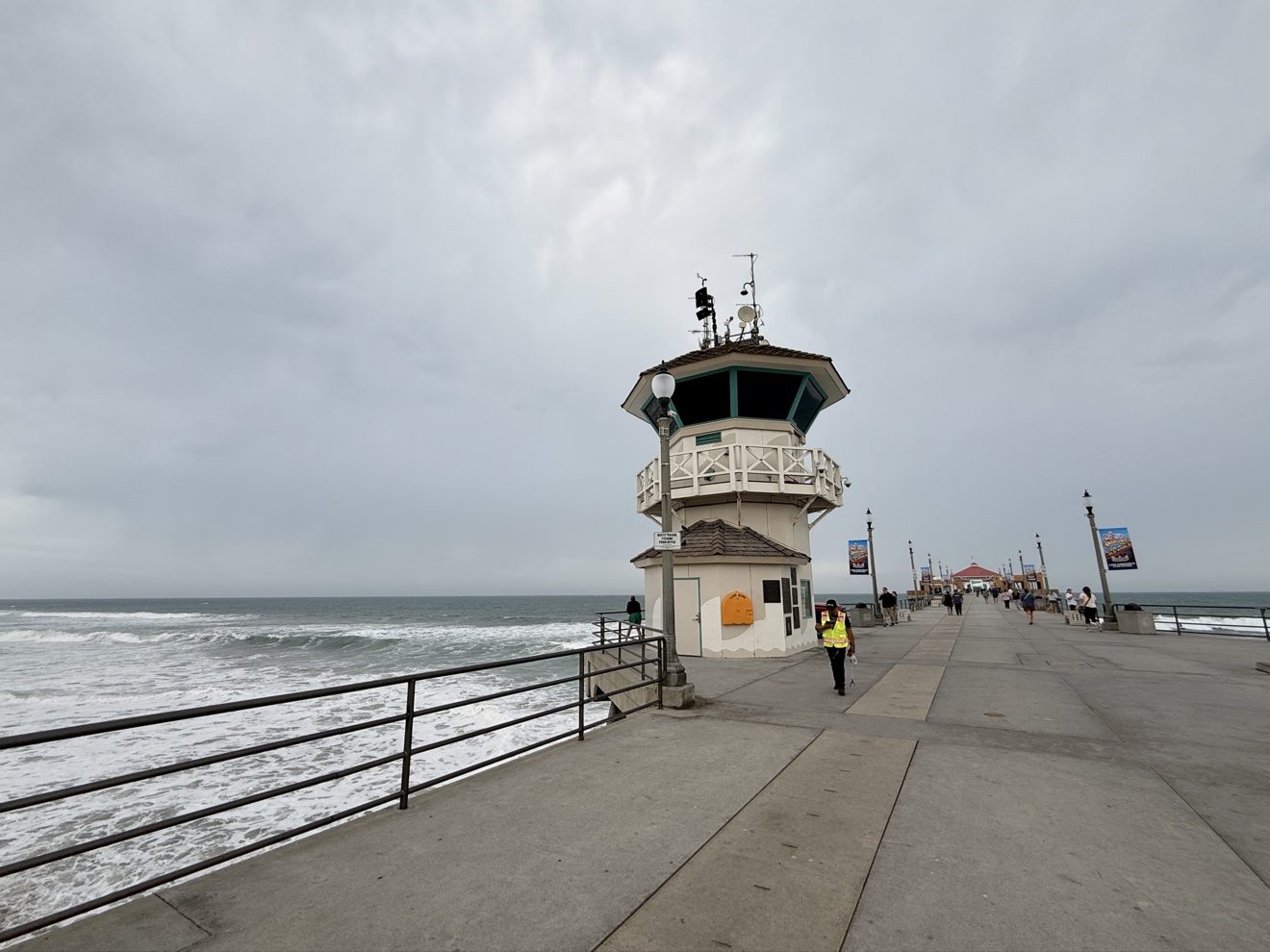 The lifeguard tower on the Huntington Beach Pier under heavy storm clouds on Saturday morning, Oct. 10, 2026, as surf built ahead of Tropical Storm Rachel. A coastal flood warning is in effect for Orange County coastal areas through 3 p.m. Sunday.
